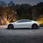 Tesla logo and falling stock chart over electric vehicle production line background, symbolizing market slowdown.