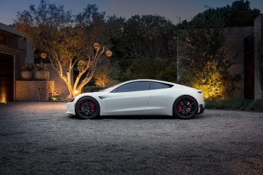 Tesla logo and falling stock chart over electric vehicle production line background, symbolizing market slowdown.
