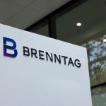 Brenntag chemical logistics facility with delivery trucks and containers, reflecting market downgrade and sector slowdown.