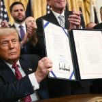 US President Donald Trump displays the GENIUS Act (Guiding and Establishing National Innovation for US Stablecoins Act), which codifies the use of stablecoins -- cryptocurrencies pegged to stable assets like the US dollar or US bonds -- after signing it in the East Room of the