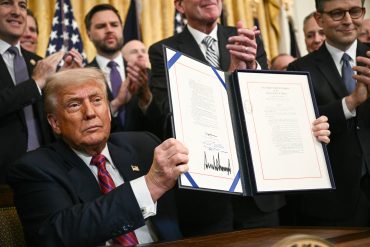 US President Donald Trump displays the GENIUS Act (Guiding and Establishing National Innovation for US Stablecoins Act), which codifies the use of stablecoins -- cryptocurrencies pegged to stable assets like the US dollar or US bonds -- after signing it in the East Room of the