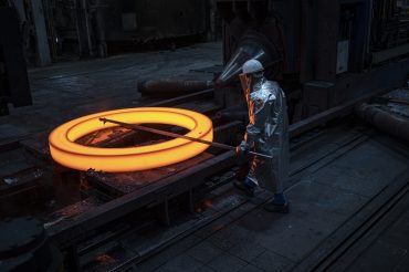 Arbeitssicherheit, Dortmund, OSH, Produktionsanlage, Produktionsmitarbeiter, Ringe, Rohlinge, Schutzkleidung, Silbermantel, blanks, measuring, messen, nahtlos gewalzte Ringe, production plant, production worker, protection gear, rings, rothe erde Ringe, rothe erde rings, seamless rolled rings, silver coat, thyssenkrupp rothe erde, Adult, Architecture, Building, Factory, Hardhat, Helmet, Male, Man, Person, Worker Ein glühender Ring. Der Mitarbeitende vermisst den Ring.