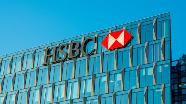 HSBC logo on global headquarters with financial charts reflecting profit drop and China real estate exposure