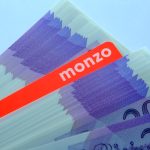 Monzo logo on smartphone, FCA document in background symbolizing compliance enforcement