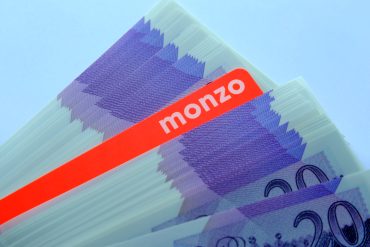 Monzo logo on smartphone, FCA document in background symbolizing compliance enforcement