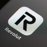 Revolut app interface on smartphone, with digital finance icons, charts, and a rising valuation arrow, symbolizing fintech expansion and revenue growth.