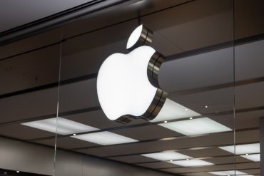 Apple logo in front of EU flags and courthouse backdrop, symbolizing the legal challenge over App Store regulations under the Digital Markets Act.