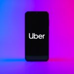 Uber app on smartphone with upward stock chart and tax document background