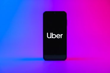 Uber app on smartphone with upward stock chart and tax document background