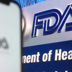 FDA headquarters logo with U.S. flag in background, representing regulatory upheaval in biotech sector