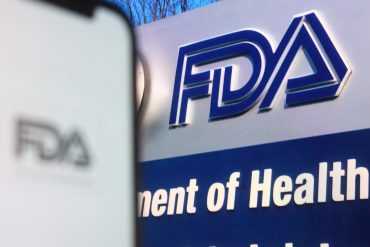 FDA headquarters logo with U.S. flag in background, representing regulatory upheaval in biotech sector