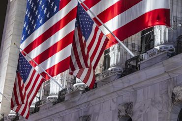 Night view of the illuminated exterior of New York Stock Exchange with a big American flag from the front facade. NYSE building has the style of classical architecture of Greece with columns, the inscription New York Stock Exchange and US flags hanging. The financial organization at Wall Street is a symbol for the global and American Economy as one of the most powerful financial institution located in Wall Street at lower Manhattan in New York City, United States of America. The US stock market is reacting with heavy losses after president Trump tariffs announcement on April 2025. November 2024 in NYC, USA (