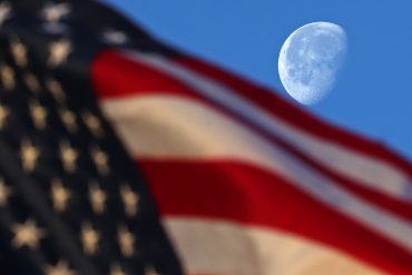 The waning gibbous Moon sets behind a flag at NASA’s Michoud Assembly Facility in New Orleans just after sunrise on Wednesday,