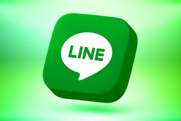 Line app. Close-up of a smartphone chat screen where an AI assistant books a taxi and pays a merchant inside the same thread.