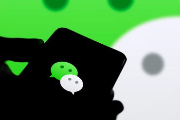 Close-up of a smartphone chat screen where an AI assistant books a taxi and pays a merchant inside the same thread.