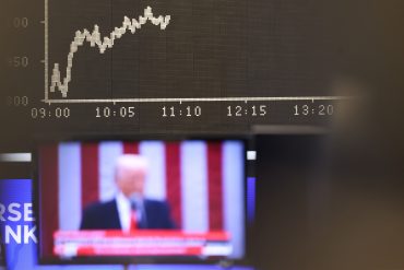 The DAX Index yield curve displayed on a screen beyond a television with an image of US President Donald Trump at the Frankfurt Stock Exchange in Frankfurt, Germany, on Thursday, April 3, 2025. Global financial markets were hit by a sweeping selloff after President Donald Trump's bid to remake the world trading order proved more aggressive than expected. Photographer: Alex Kraus/Bloomberg via Getty Images