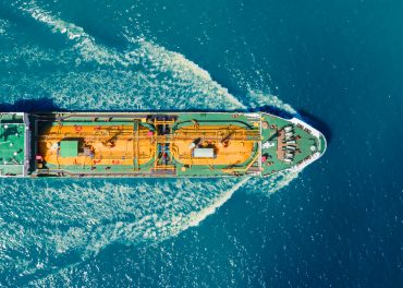 Aerial view of a Sempra liquefied gas tanker sailing through blue waters, with bright yellow LPG storage tanks visible on deck.