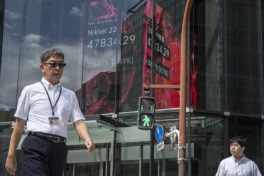 Pedestrians pass an electronic board showing the Nikkei 225 index surpassing 48,000 in Tokyo on October 6, 2025.