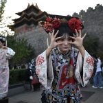 Women wearing traditional Chinese costumes pose for photographs as they visit the surroundings of the Forbidden City in Beijing during China's National Day Golden Week holiday