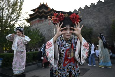 Women wearing traditional Chinese costumes pose for photographs as they visit the surroundings of the Forbidden City in Beijing during China's National Day Golden Week holiday