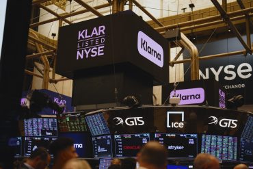 Trading floor at NYSE showing Klarna logo and stock data.