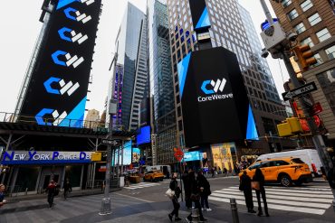 CoreWeave branding displayed on digital screens in New York’s Times Square near NASDAQ, as the AI cloud provider reports $5.1 billion in 2025 revenue and a $66.8 billion backlog.