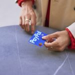 Hand holding a PayPal payment card, symbolizing PayPal’s core digital payments business during a period of modest growth and operational reset.