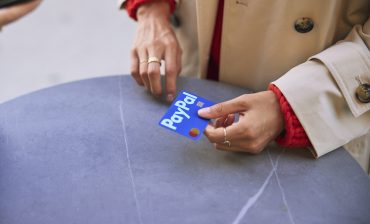 Hand holding a PayPal payment card, symbolizing PayPal’s core digital payments business during a period of modest growth and operational reset.