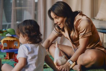 Woman wearing a Whoop fitness tracker while playing with her young child as Whoop expands its women’s health panel and women’s biomarker tracking platform.