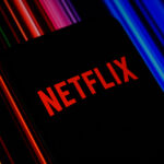 Mobile phone displaying the Netflix logo, representing Netflix Q3 earnings, advertising revenue, streaming growth, operating margin and Netflix stock performance