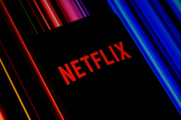 Mobile phone displaying the Netflix logo, representing Netflix Q3 earnings, advertising revenue, streaming growth, operating margin and Netflix stock performance