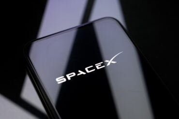 Mobile phone displaying the SpaceX logo, representing the SpaceX spectrum deal, Starlink Mobile, 800 MHz low-band spectrum, direct-to-device service and U.S. wireless competition
