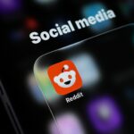 Reddit app icon displayed on a smartphone, representing Reddit Q3 earnings, record profit, U.S. user decline, advertising growth and pressure from Google AI search traffic